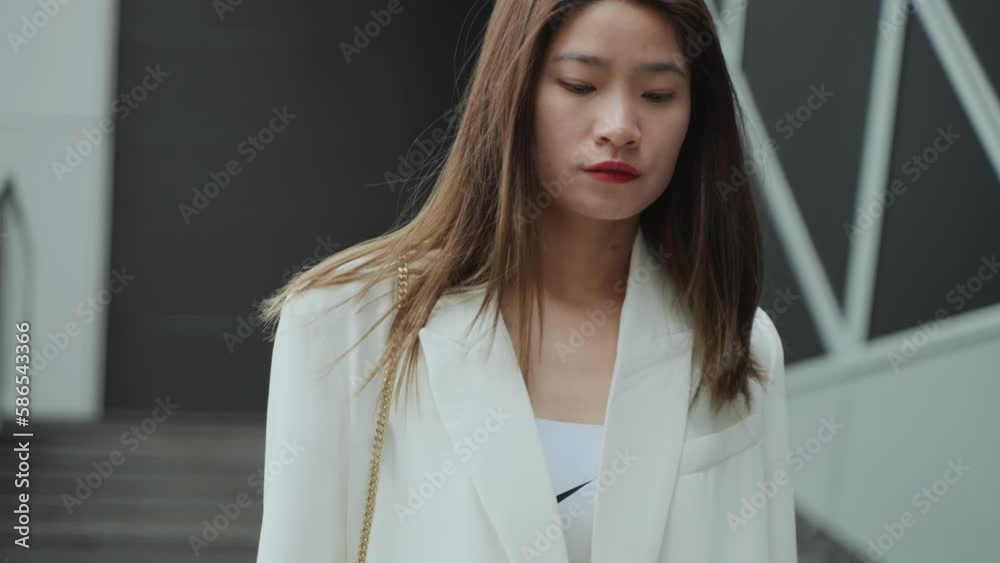 Slow motion of Charming young Asian girl in a white suit walking on the city street Slow motion of Charming young Asian girl in a white suit walking on the city street