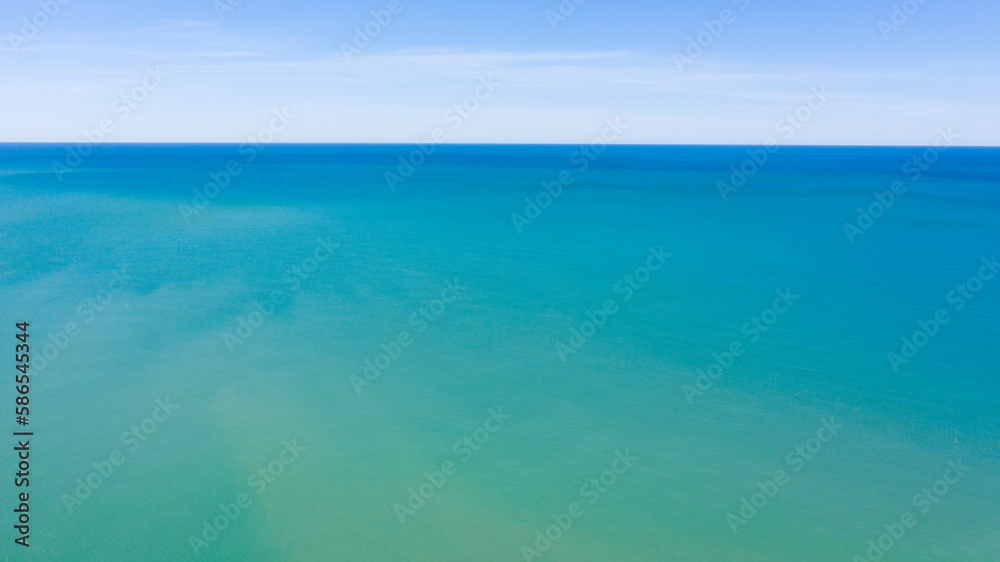 Aerial view of the blue waters of the Mediterranean Sea and specifically of the Tyrrhenian Sea from Sicily. Sunlight is reflected on the surface of the water. Sky and clouds are on background.
