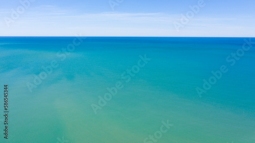 Aerial view of the blue waters of the Mediterranean Sea and specifically of the Tyrrhenian Sea from Sicily. Sunlight is reflected on the surface of the water. Sky and clouds are on background.