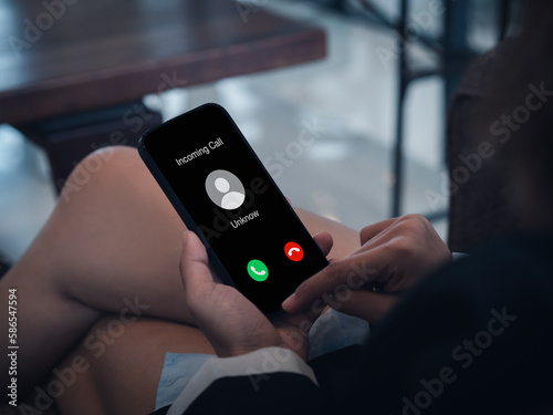 Incoming call with unknown caller, malicious phone calls concept. Unknown number displayed showing on smart mobile phone in business person hand. Spam and robocalls, scam call alert.