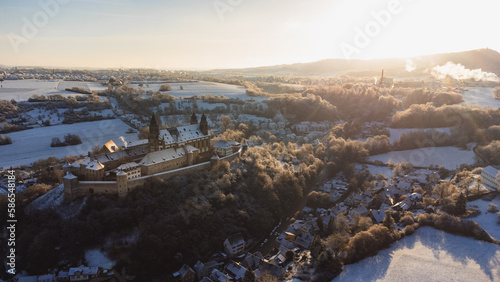 Fototapeta Naklejka Na Ścianę i Meble -  A castle that looks like Hogwarts in a winter landscape. The monastery looks like a castle, or a castle from the Middle Ages. The castle was photographed from the air with a drone