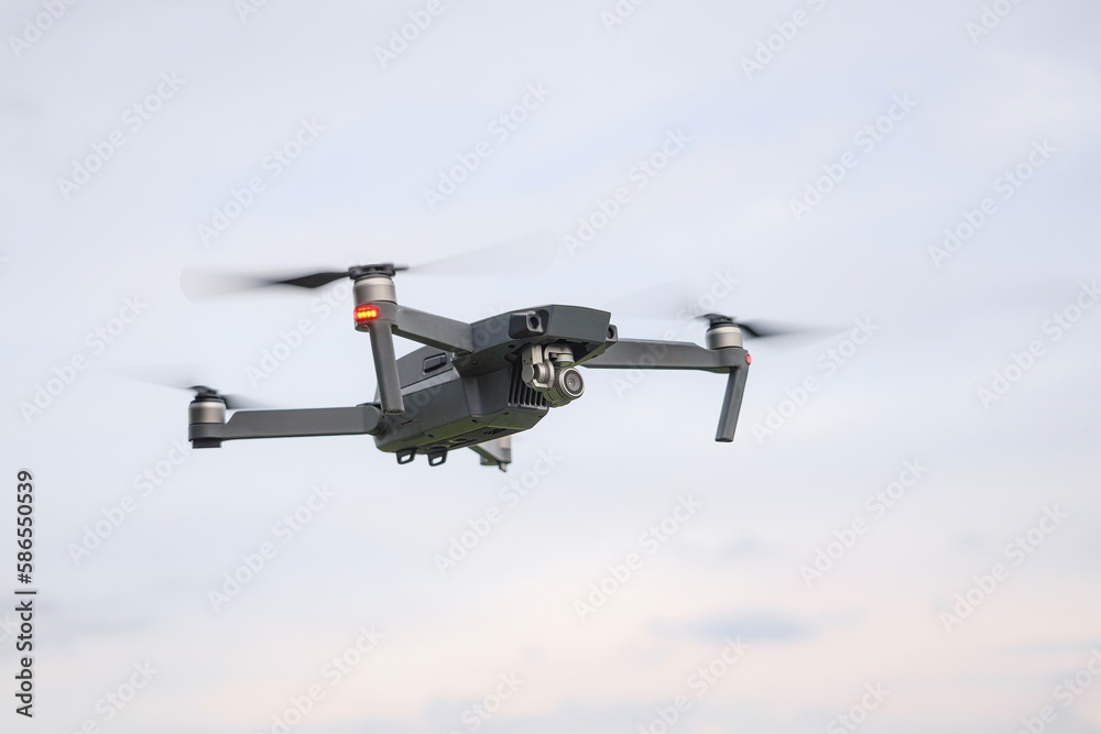 A flying drone against a cloudy sky in cloudy weather takes pictures of the surface of the earth. A flying drone against a cloudy sky in cloudy weather takes pictures of the surface of the earth.