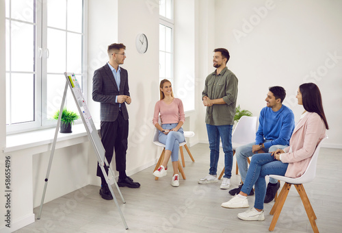 Young business team having a work meeting in a modern office. Group of happy millennial workers listening to a presentation by their manager, discussing new projects and making suggestions