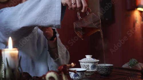 female tea master pours hot tea into a bowl, steam hovers over the bowl, close-up