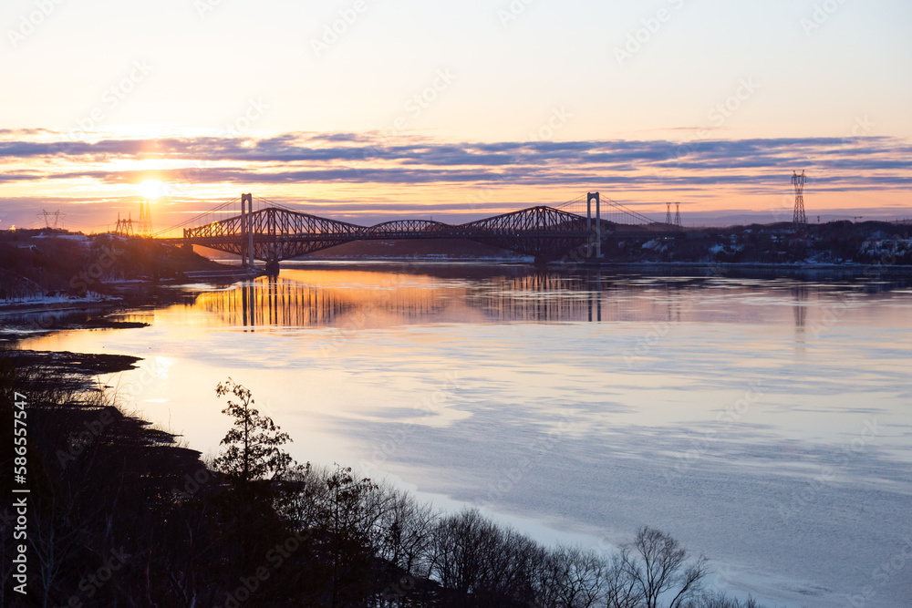 The 1970 Pierre-Laporte and the 1904 Quebec bridges over the St. Lawrence river in silhouette seen from the Cap-Rouge cliff during a beautiful pink and orange spring sunrise, Quebec City, Quebec, Cana