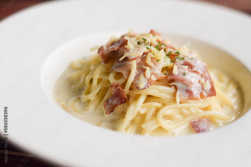 Spaghetti Carbonara in white dish on wood table