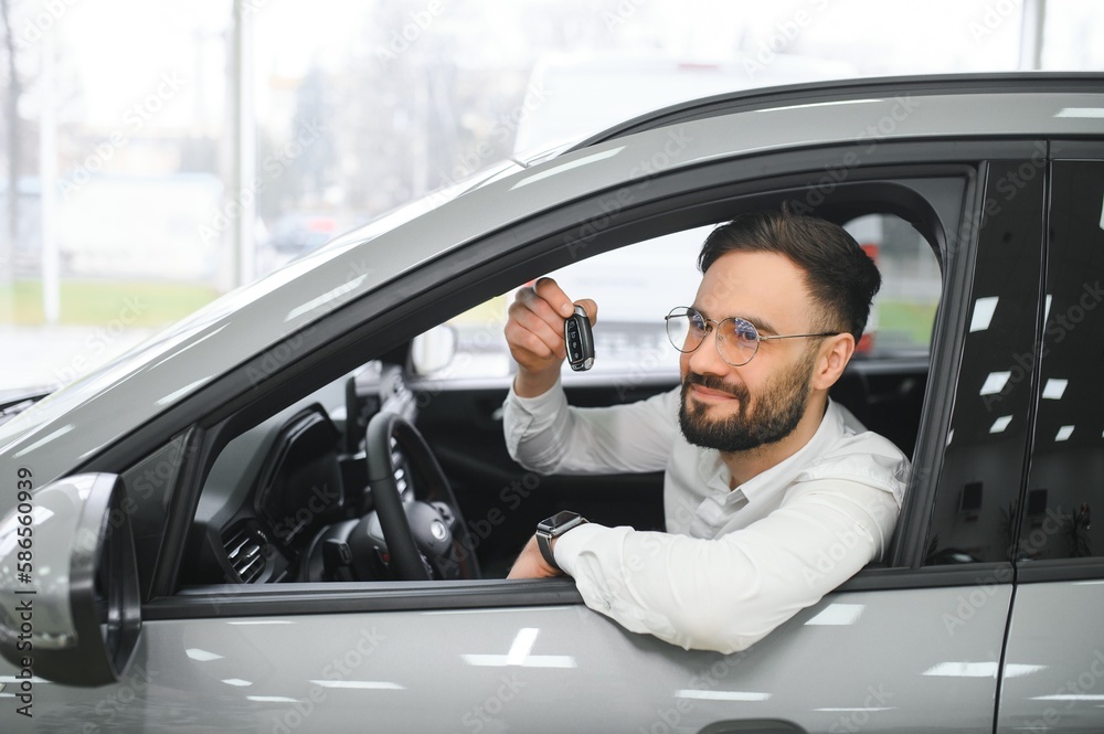Naklejka premium Yes, that's my new car. Customer in car dealership. Young man with keys in hand