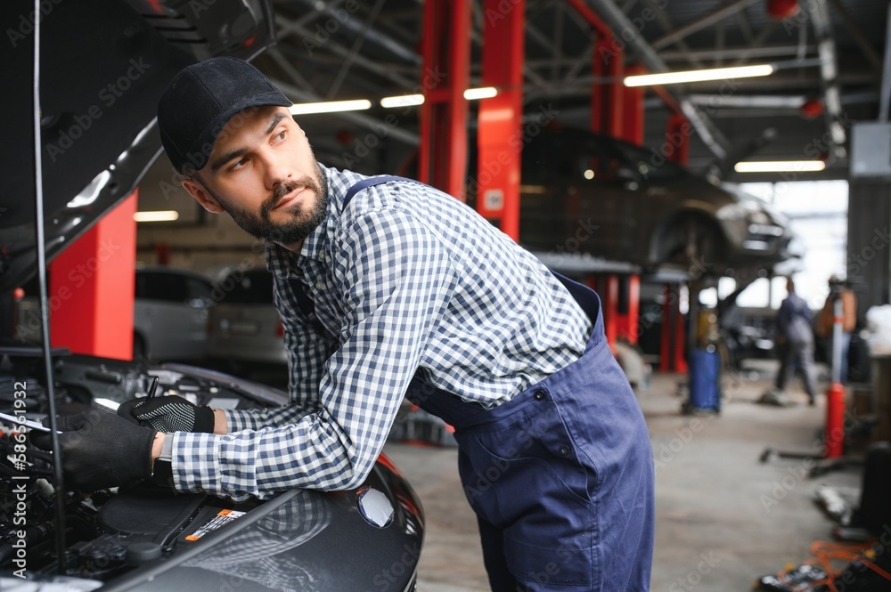 Mechanic examining under hood of car at the repair garage Mechanic examining under hood of car at the repair garage