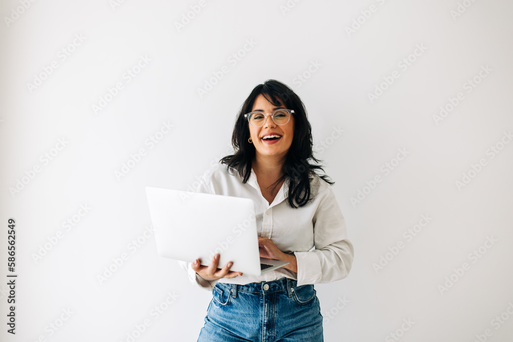 Business woman smiling and using a laptop in an office Business woman smiling and using a laptop in an office
