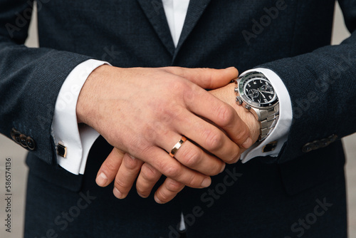Hands of a businessman with a luxury watch on the background of a jacket and a white shirt. Business meeting and time for work