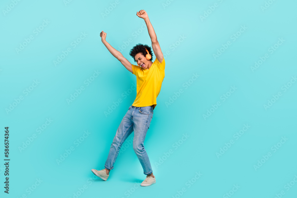 Full body photo of delighted carefree man raise fists dancing listen music isolated on turquoise color background
