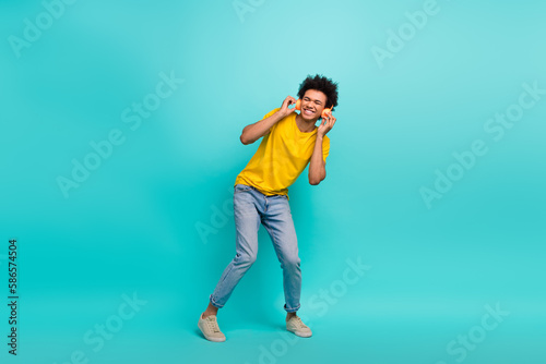 Full length photo of carefree crazy person hands touch headphones dancing isolated on teal color background