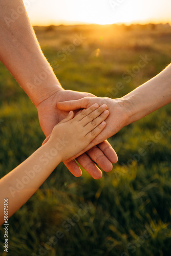 Mom dad and child holding hands together during a walk in summer. Family hands and adult support. A happy family