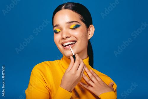 Glamour girl: Generation Z woman applying lip gloss in a studio