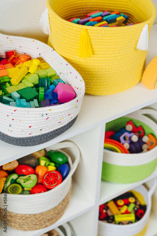 Colorful storage baskets on shelves. White shelving with rainbow wooden