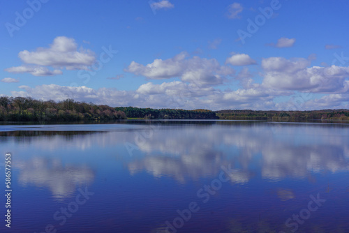 A calm sunny day with a view across Eccup Reservoir creating stunning reflections of blue sky and white clouds, Leeds, England, West Yorkshire, UK. 