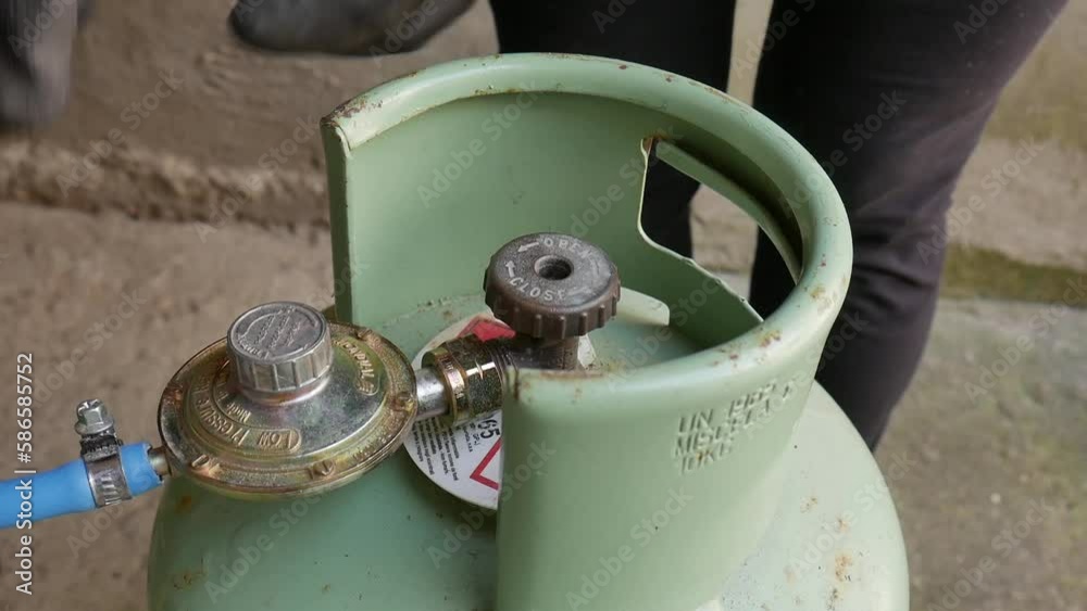 LPG cylinder connection with pressure regulator. close-up of a technician connecting a gas cylinder. pvc pipe. bottle sealed and ready to use.