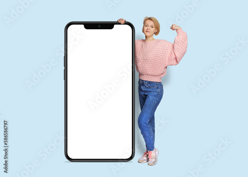 Full body side view young woman wear pink casual sweater huge big blank screen mobile cell phone with area use smartphone isolated on plain pastel light background.