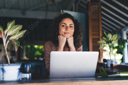 Portrait of skilled female programmer with modern laptop computer looking at camera during remote working at cafe terrace, millennial woman with digital netbook posing during freelance distance job photo