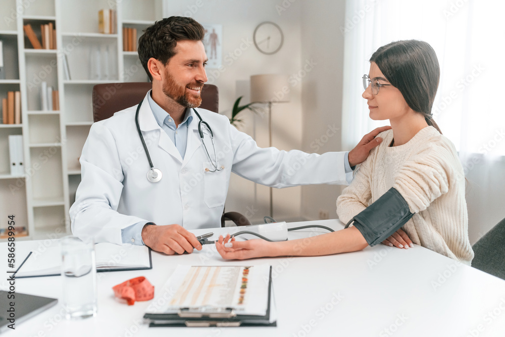 Blood pressure measurement. With woman. Doctor in formal clothes is working in the cabinet Blood pressure measurement. With woman. Doctor in formal clothes is working in the cabinet