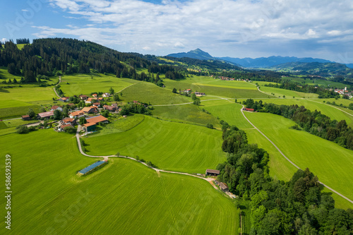 aerial view of green fields of allgaeu and meadows and alps in the background