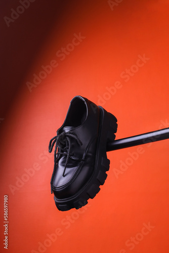 Flying black leather womens isolated on red background. Fashionable stylish casual shoes. Creative minimalist layout with footwear Mock up for your design Advertising for shoe store