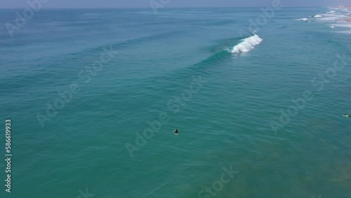 Aerial drone view of surfer sitting on his board watching the waves coming by. photo