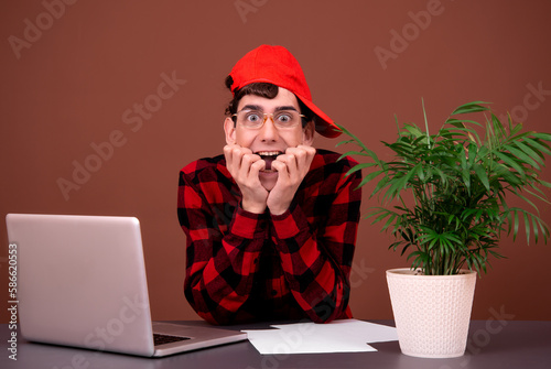 Young funny nerd is working on a laptop.