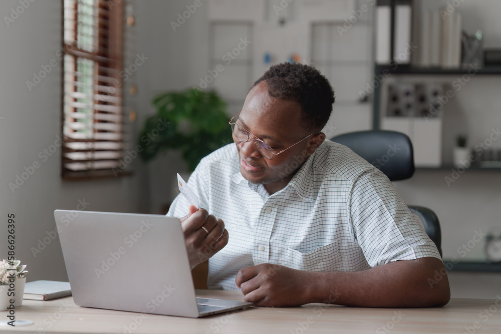 Young african american man using mobile cell phone hold credit bank card. banking application, online shopping concept Young african american man using mobile cell phone hold credit bank card. banking application, online shopping concept