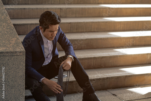 Businessman sitting stressed on the stairs after failing a job interview