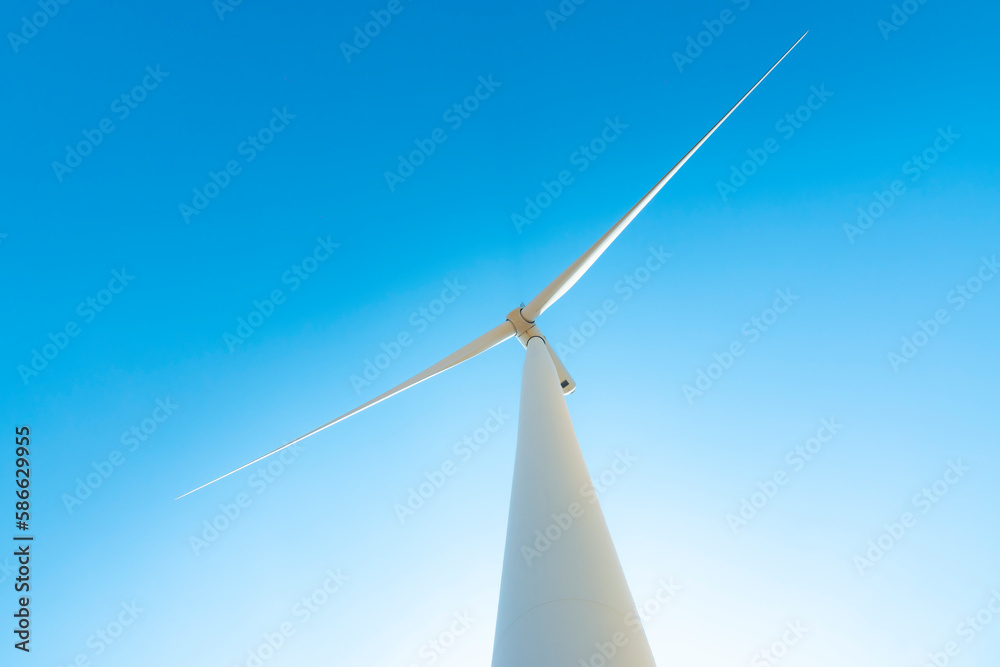 Large electric wind turbines on blue sky. Renewable energy, a new energy business alternative that is friendly to the environment and community. low angle shot. Large electric wind turbines on blue sky. Renewable energy, a new energy business alternative that is friendly to the environment and community. low angle shot.