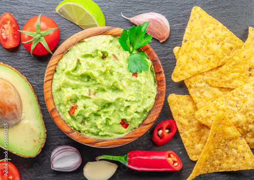 Guacamole sauce and  guacamole ingredients, popular Mexican food, on slate serving board. Top view.