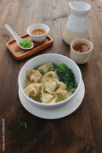 wonton soup dish with celery, spring onions and chili sauce