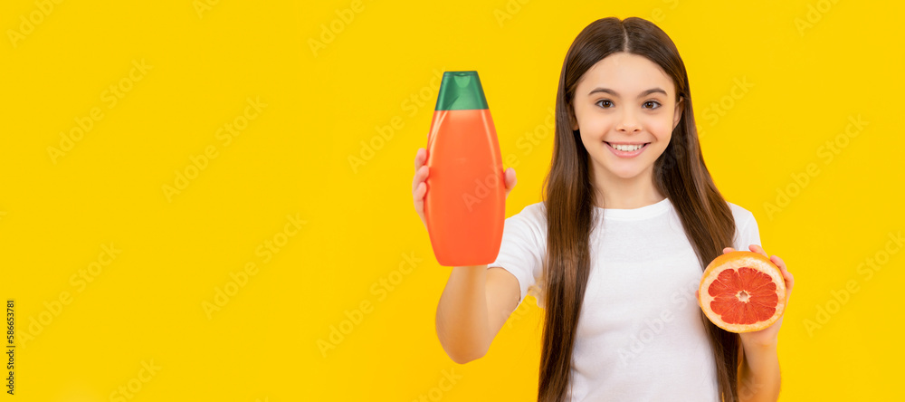 smiling kid hold hair conditioner bottle and grapefruit on yellow background, citrus. Banner of child girl hair care, studio poster header with copy space. smiling kid hold hair conditioner bottle and grapefruit on yellow background, citrus. Banner of child girl hair care, studio poster header with copy space.