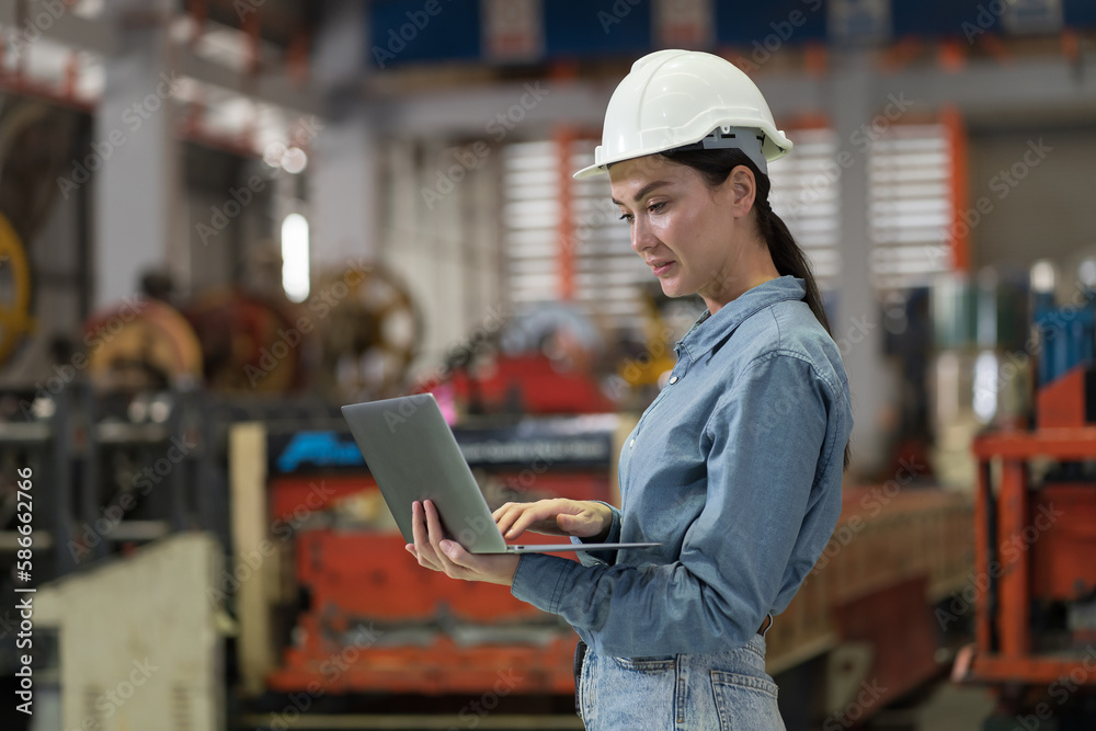 Female factory worker working using laptop computer inspecting quality of production at manufacturing lines in factory. Female inspector with laptop computer checking product material in factory Female factory worker working using laptop computer inspecting quality of production at manufacturing lines in factory. Female inspector with laptop computer checking product material in factory