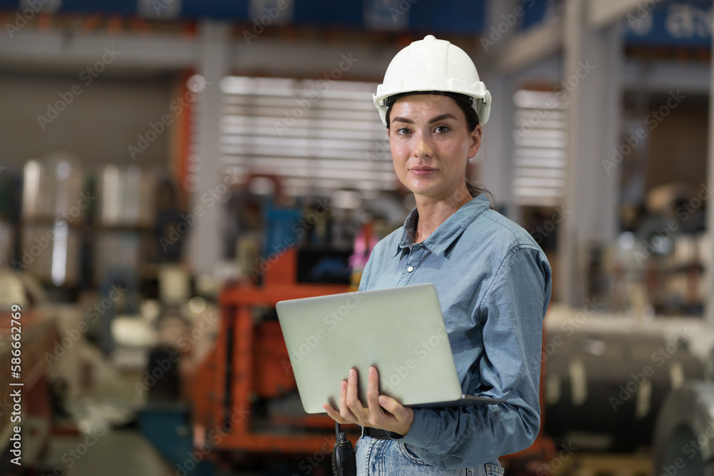 Female factory worker working using laptop computer inspecting quality of production at manufacturing lines in factory. Female inspector with laptop computer checking product material in factory