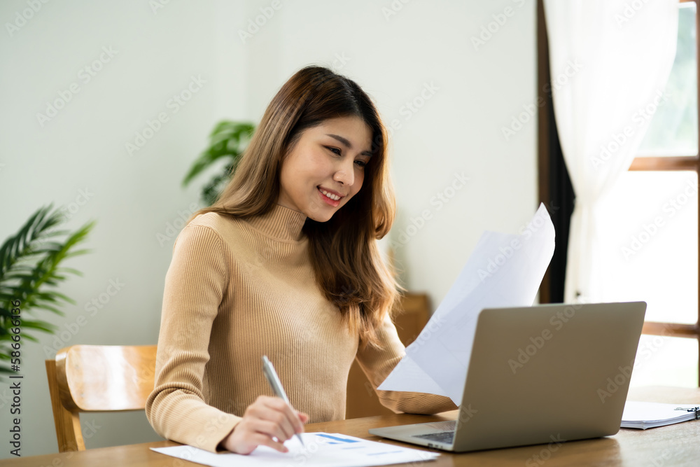 Happy beautiful Asian woman using computer laptop for work online at living room. Happy beautiful Asian woman using computer laptop for work online at living room.