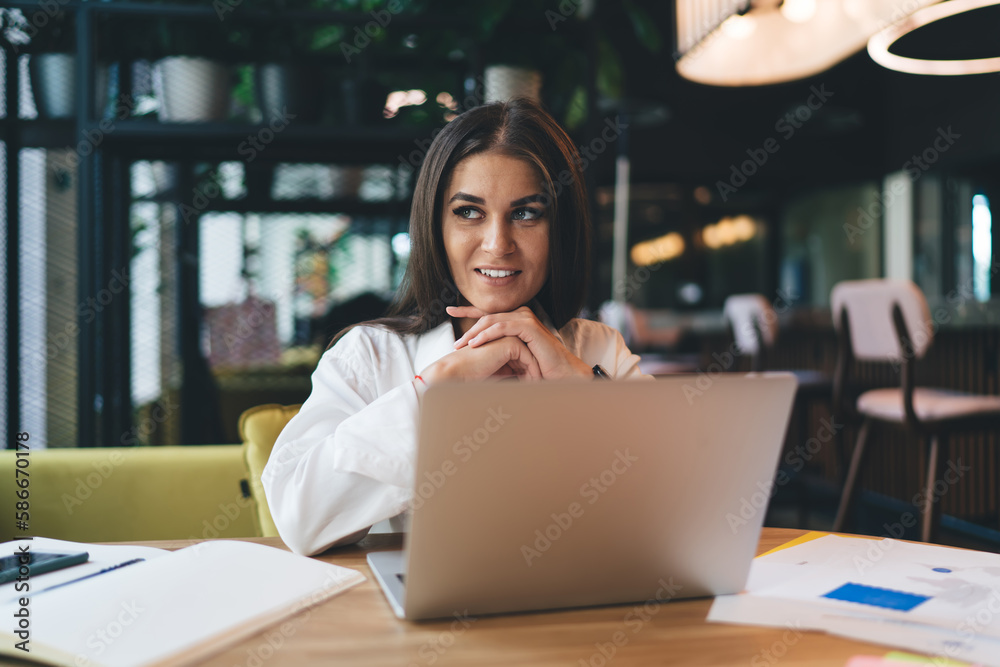 Cheerful woman browsing laptop during work on project
