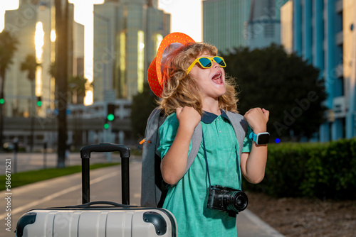 Portrait of happy child traveler with luggage. Positive little tourist with suitcase ready to travelling. Happy kid tourist with baggage going to travel on holidays.