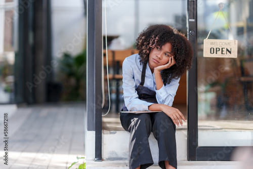 Female shopkeeper sitting stressed out at the store entrance frustrated by the economic impact. Free Download Female shopkeeper sitting stressed out at the store entrance frustrated by the economic impact. - GFXLoad