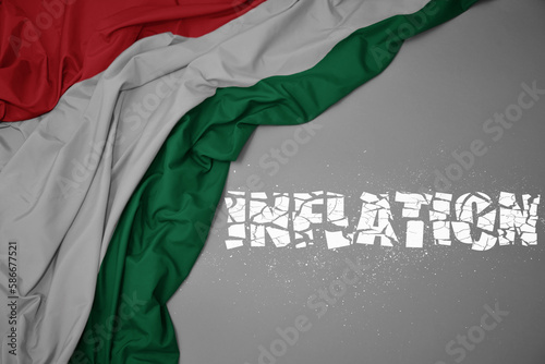 waving colorful national flag of hungary on a gray background with broken text inflation. 3d illustration