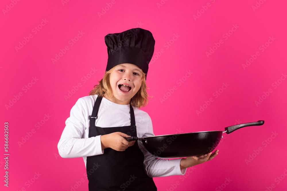 Child chef cook with pan. Kid chef cook prepares food on isolated studio background. Kids cooking. Teen boy with apron and chef hat preparing a healthy meal. Child chef cook with pan. Kid chef cook prepares food on isolated studio background. Kids cooking. Teen boy with apron and chef hat preparing a healthy meal.