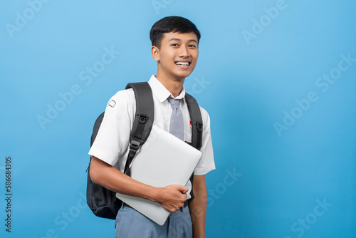 Indonesian senior high school student Holding and using laptop isolated on blue background. Pelajar siswa SMA (Sekolah menengah atas) Indonesia photo