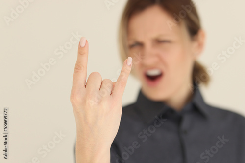 Blurry screaming woman shows horns gesture with fingers