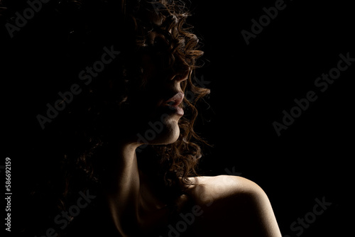 Sensual portrait silhouette of beautiful curly woman in backlight on a black background photo
