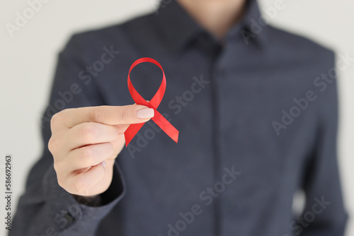 Woman holds red ribbon representing fight against AIDS