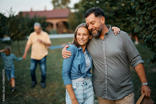 Foto Embraced teenager girl and her father walk through backyard.