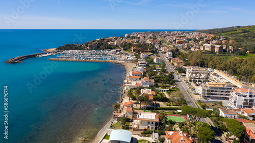 Aerial view of the marina and port of Santa Marinella, in the Metropolitan City of Rome, Italy. In the background the town overlooking the Tyrrhenian Sea. There are many boats moored at the harbour.