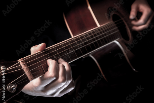 close-up of the hands of a musician playing an acoustic guitar