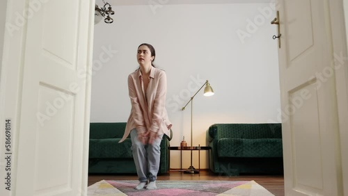 Pretty young Caucasian woman wearing casual clothes learning to charleston in home. Concept of dance training and advertising photo